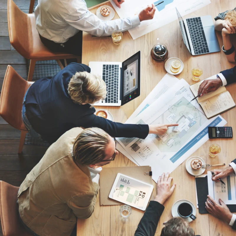 an overhead shot of a group of people discussing organization at a conference table